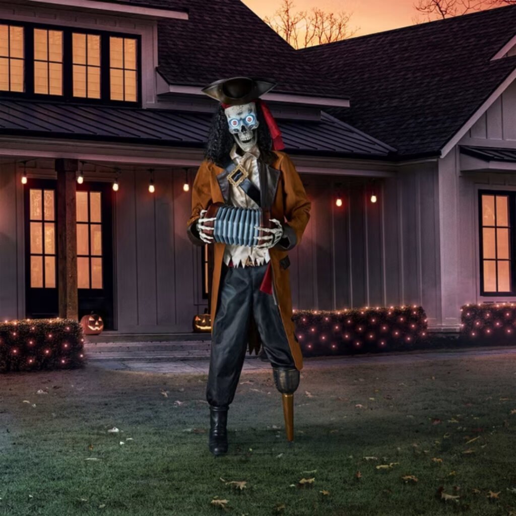 Member's Mark 7 ft animated pirate skeleton with glowing LED eyes playing an accordion on a front lawn at dusk