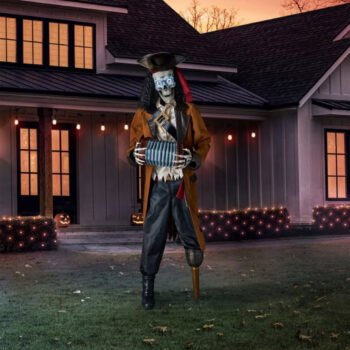 Member's Mark 7 ft animated pirate skeleton with glowing LED eyes playing an accordion on a front lawn at dusk