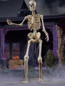 6.5 ft Home Accents Holiday Ultra Skelly standing in front of a Halloween porch