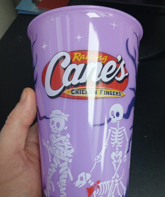 Raising Cane's purple glow-in-the-dark Halloween cup with skeletons and a mummy